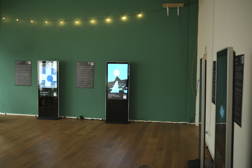 A gallery wall, with two digital frames, one with a still from Pharmageddon, and one with a still from Star Window.